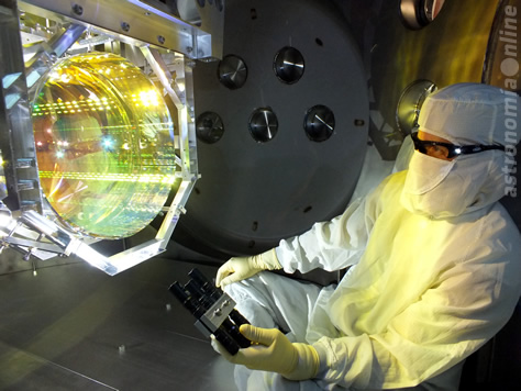 Antes de sellar la cámara y encender las bombas de vacío, un técnico inspecciona una de las ópticas principales del detector LIGO, un espejo, iluminando su superficie a un cierto ángulo. Es fundamental que no haya contaminación en ninguna de las superficies ópticas del instrumento para la operación de LIGO. Créditos de la imagen: LIGO / Caltech / MIT.